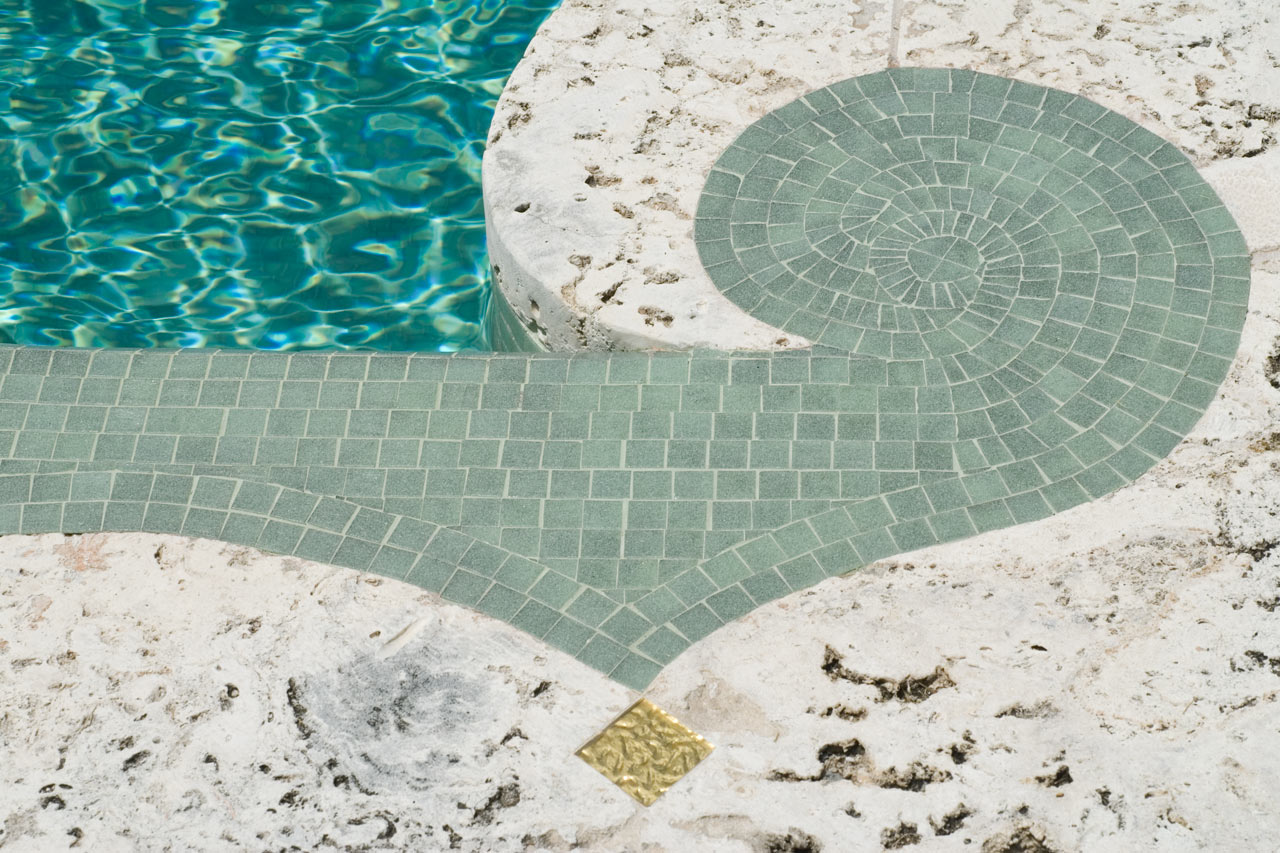 keystone, glass tile, gold leaf of an Oval stone & mosaic pool in Miami Beach designed by Maria de la Guardia & Teofilo Victoria of DLGV Architects & Urbanists